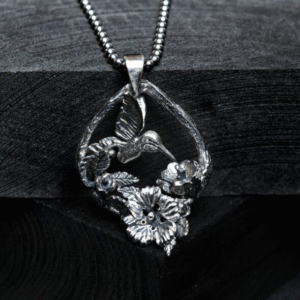 Pandantiv handmade din argint 925 cu pasăre colibri și flori hibiscus, fotografiat în decor de primăvară cu lavandă – bijuterie unicat inspirată din natură