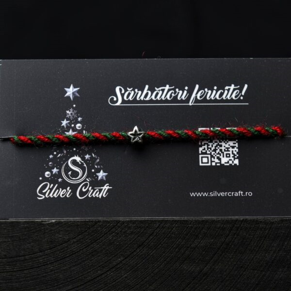 Charm steluță mică din argint 925, lucrat manual, pe șnur roșu și verde, așezat pe carton festiv tematic de Crăciun – bijuterie delicată pentru cadouri de iarnă.