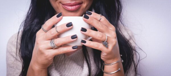Inel modernist din argint 925 purtat alături de alte bijuterii, în timp ce modelul ține o ceașcă de cafea – imagine caldă și expresivă.