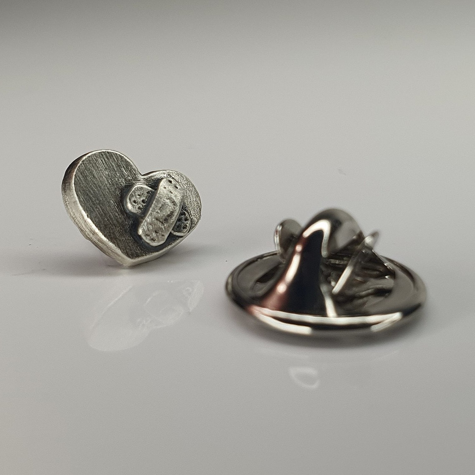 Detaliu cu broșa‑pin în formă de inimă din argint 925, cu plasture simbolic sculptat manual